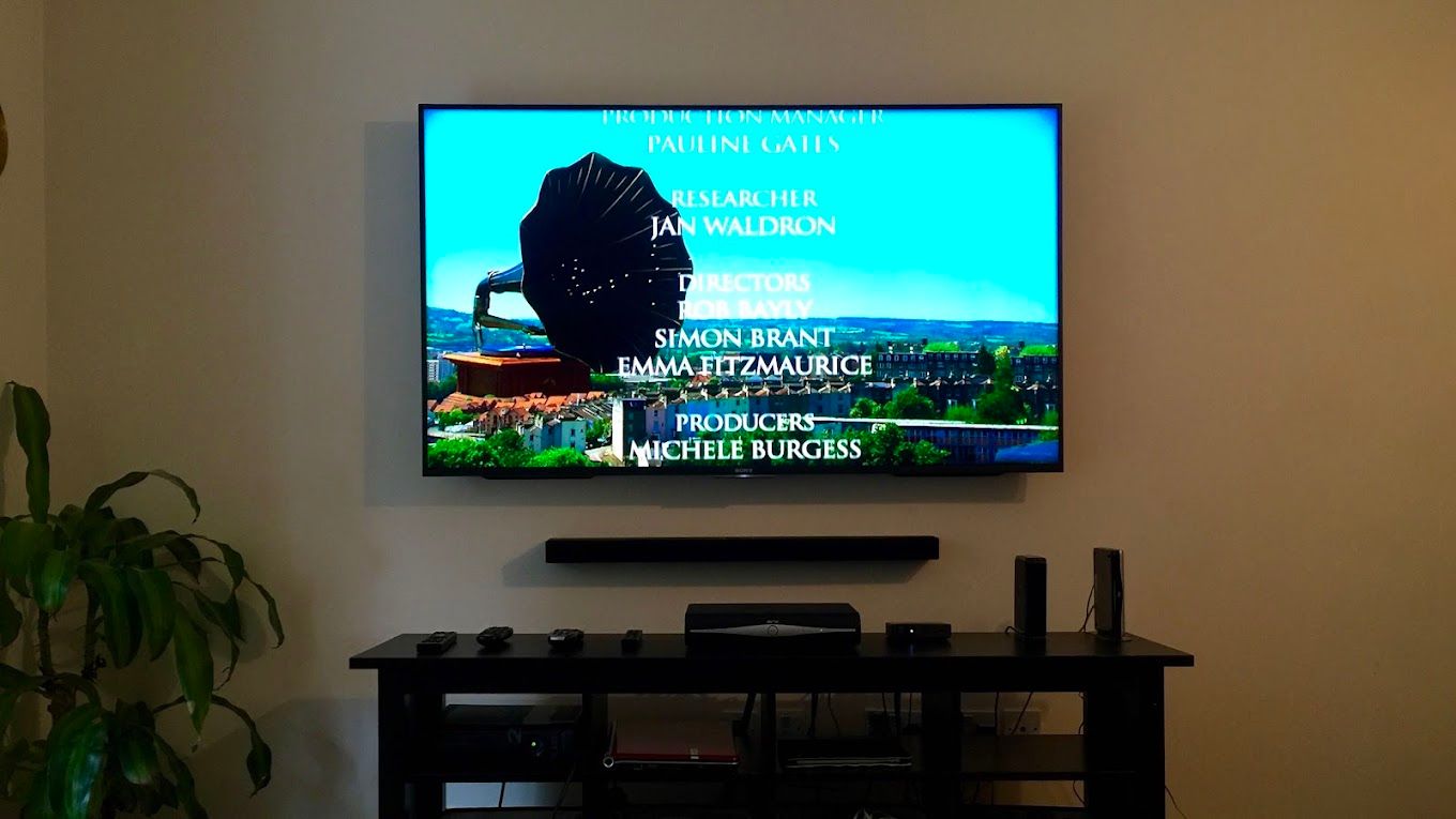 A TV mounted on a living room wall with no cables showing, and a soundbar fitted neatly below