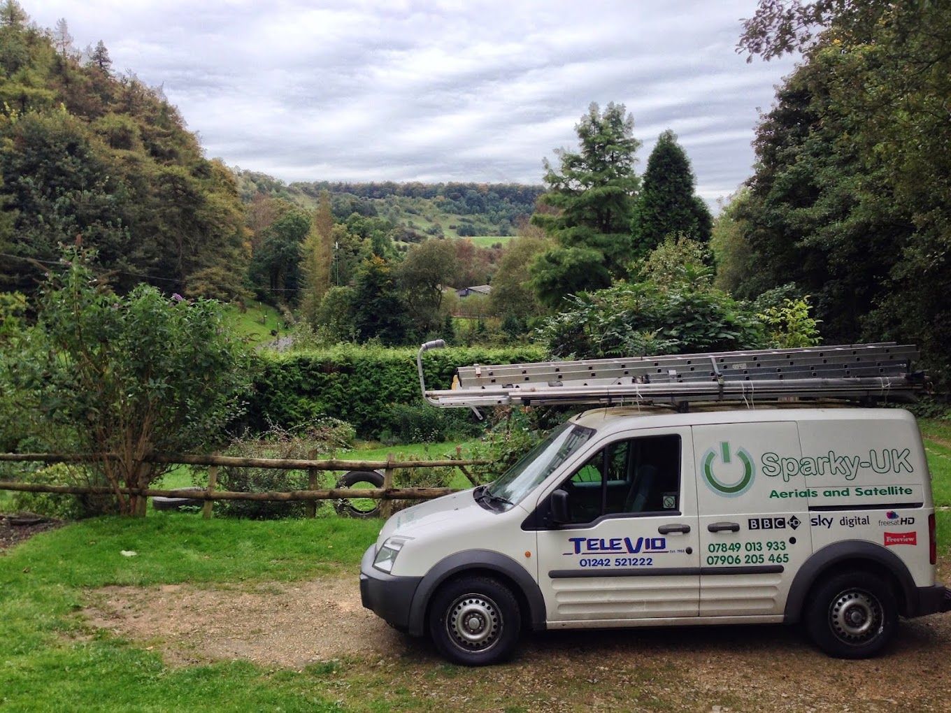 The Sparky-UK van parked above a wooded Cotswold valley